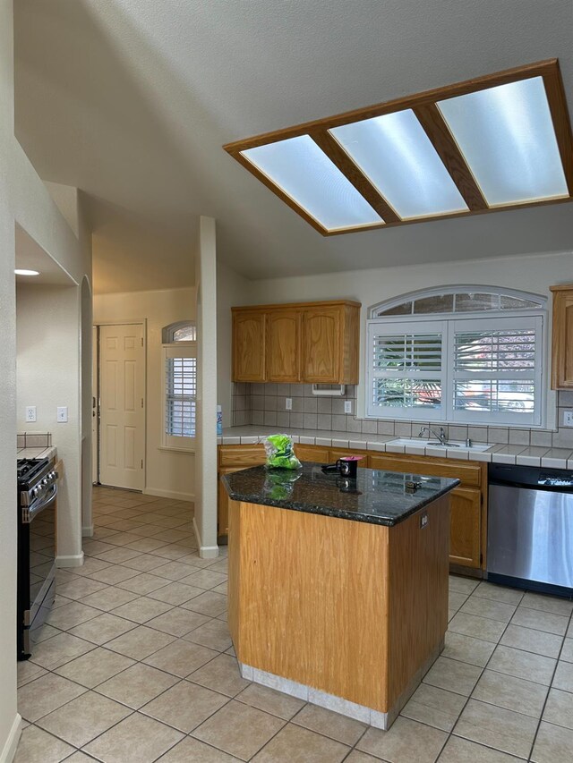 220 S Double Tree Way, Madera, CA 93637 - kitchen featuring stainless steel appliances, a kitchen island, tasteful backsplash, light tile patterned floors, and dark stone counters