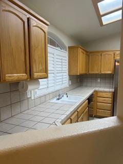 220 S Double Tree Way, Madera, CA 93637 - kitchen with tile countertops, lofted ceiling, a skylight, decorative backsplash, and healthy amount of natural light