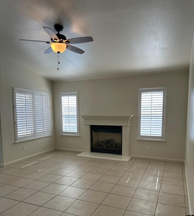 220 S Double Tree Way, Madera, CA 93637 - unfurnished living room with a textured ceiling, ceiling fan, a fireplace with raised hearth, and light tile patterned floors