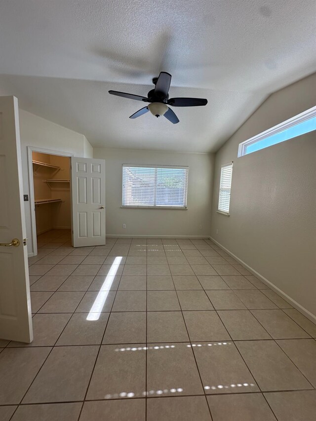 220 S Double Tree Way, Madera, CA 93637 - spare room with lofted ceiling, light tile patterned floors, a ceiling fan, and a textured ceiling