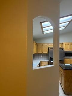 220 S Double Tree Way, Madera, CA 93637 - kitchen with stainless steel microwave, arched walkways, fridge, light brown cabinets, and light tile patterned flooring