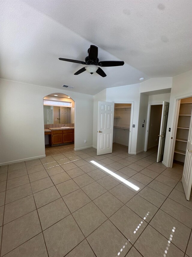 220 S Double Tree Way, Madera, CA 93637 - unfurnished bedroom with light tile patterned flooring, arched walkways, a spacious closet, a textured ceiling, and ceiling fan
