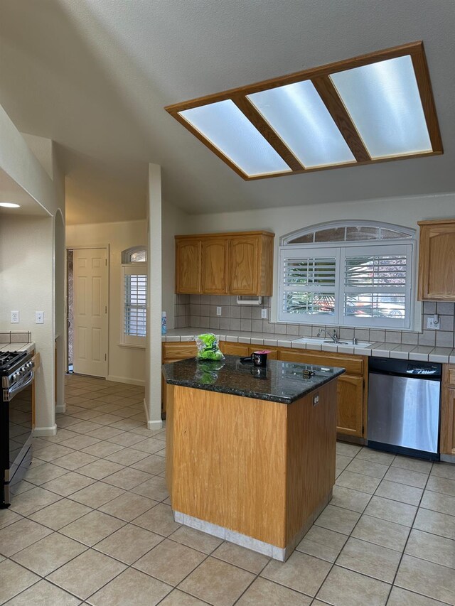 220 S Double Tree Way, Madera, CA 93637 - kitchen featuring appliances with stainless steel finishes, tasteful backsplash, light tile patterned floors, a center island, and lofted ceiling