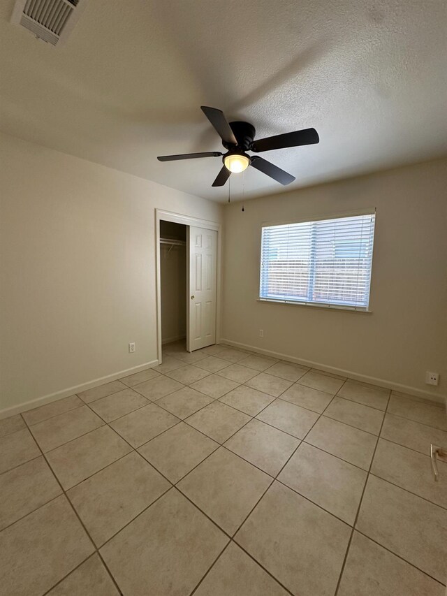 220 S Double Tree Way, Madera, CA 93637 - unfurnished bedroom featuring a closet, light tile patterned flooring, a ceiling fan, and a textured ceiling