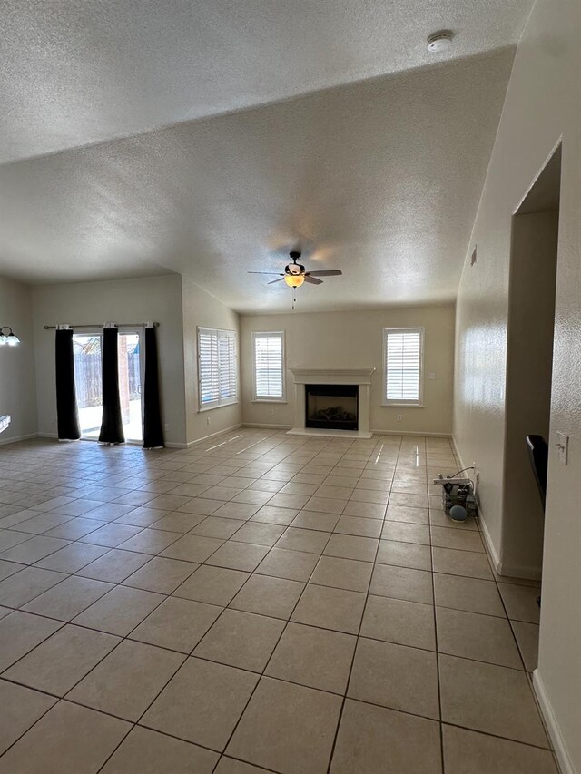 220 S Double Tree Way, Madera, CA 93637 - unfurnished living room featuring a textured ceiling, plenty of natural light, light tile patterned floors, ceiling fan, and a fireplace