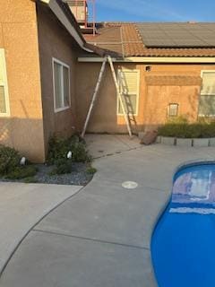 220 S Double Tree Way, Madera, CA 93637 - view of property exterior with roof mounted solar panels, stucco siding, a patio, and an outdoor pool