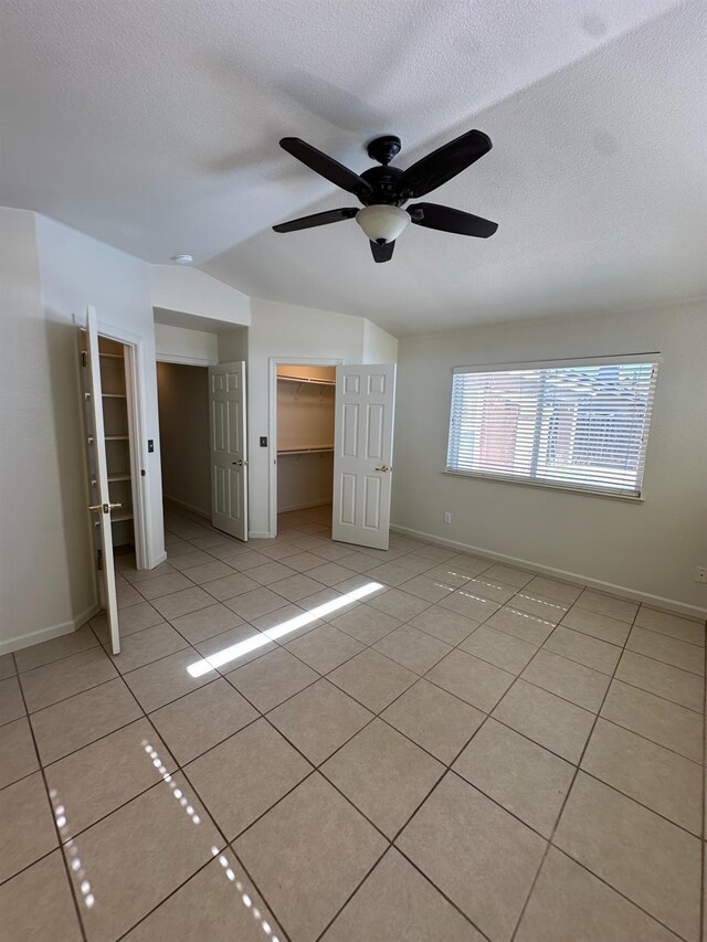 220 S Double Tree Way, Madera, CA 93637 - unfurnished bedroom with light tile patterned floors, a textured ceiling, ceiling fan, and a walk in closet
