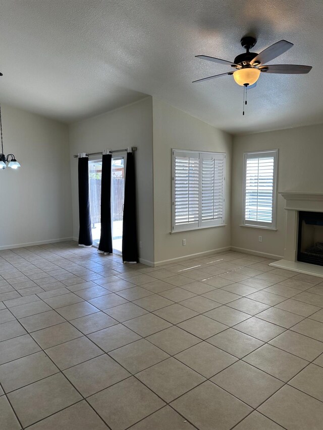 220 S Double Tree Way, Madera, CA 93637 - unfurnished living room featuring a textured ceiling, light tile patterned floors, a ceiling fan, and a fireplace with raised hearth