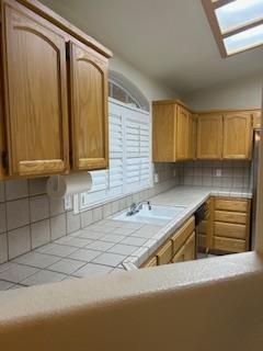 220 S Double Tree Way, Madera, CA 93637 - kitchen with tile countertops, decorative backsplash, lofted ceiling, dishwashing machine, and a skylight