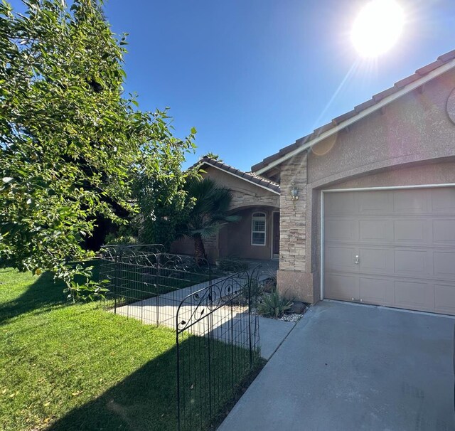 220 S Double Tree Way, Madera, CA 93637 - view of home's exterior featuring stone siding, stucco siding, a lawn, driveway, and an attached garage