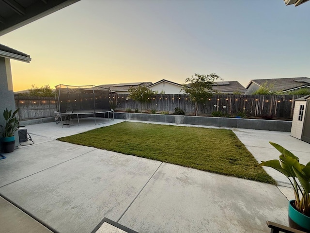 825 Spring St W, Madera, CA 93636 - yard at dusk featuring a trampoline, a patio, and a fenced backyard