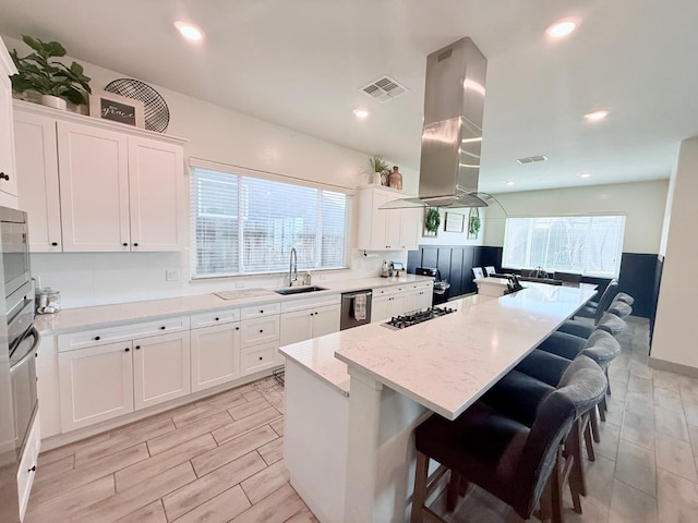825 Spring St W, Madera, CA 93636 - kitchen with dishwasher, a breakfast bar area, a kitchen island, white cabinetry, and light stone countertops