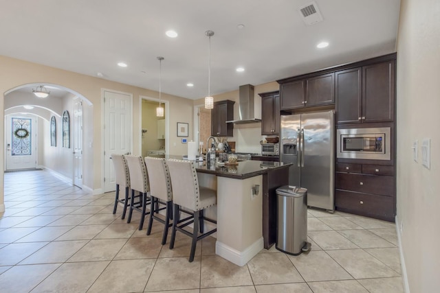 11337 N Cherry Sage Ave, Fresno, CA 93730 - kitchen featuring appliances with stainless steel finishes, wall chimney range hood, light tile patterned floors, a kitchen bar, and arched walkways