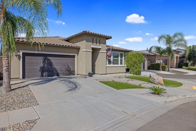 11337 N Cherry Sage Ave, Fresno, CA 93730 - mediterranean / spanish house featuring concrete driveway, stucco siding, an attached garage, and a tile roof