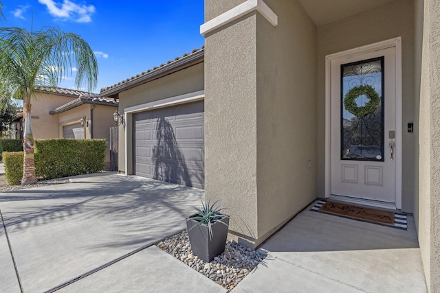 11337 N Cherry Sage Ave, Fresno, CA 93730 - doorway to property featuring stucco siding, concrete driveway, and an attached garage