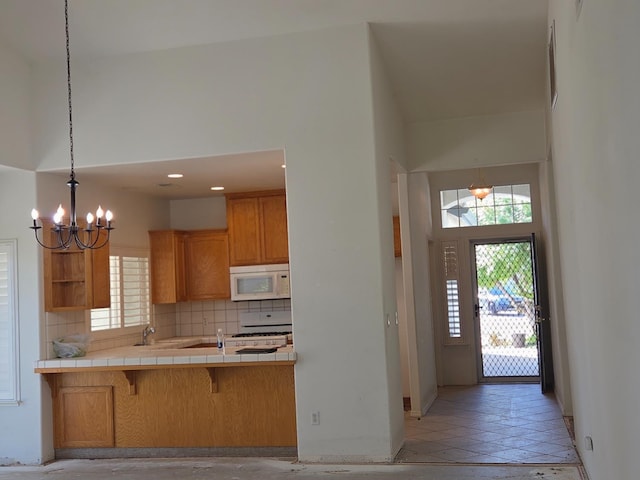2300 Sierra St Unit 101, Kingsburg, CA 93631 - kitchen with white appliances, tile countertops, a chandelier, decorative backsplash, and brown cabinets