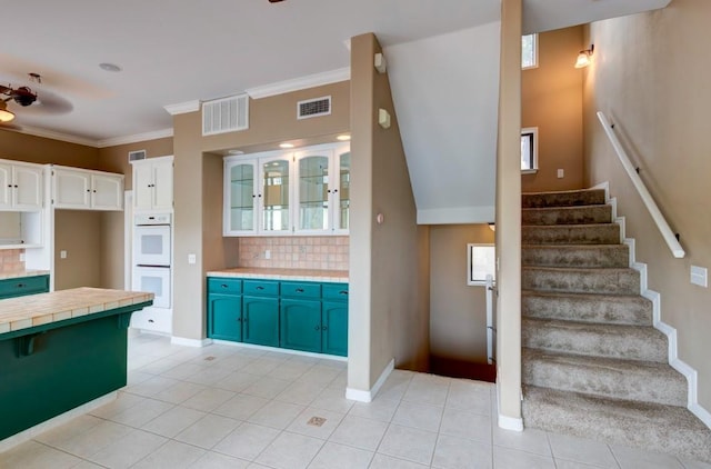 27415 Sky Harbour Rd, Friant, CA 93626 - kitchen featuring white double oven, backsplash, tile countertops, light tile patterned floors, and crown molding