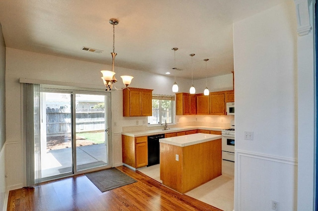 5684 W Holland Ave, Fresno, CA 93722 - kitchen with white appliances, light countertops, a kitchen island, decorative light fixtures, and light wood-style floors