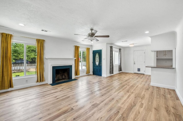 4611 N Safford Ave, Fresno, CA 93704 - unfurnished living room featuring healthy amount of natural light, a ceiling fan, light wood-style floors, a fireplace with flush hearth, and a textured ceiling