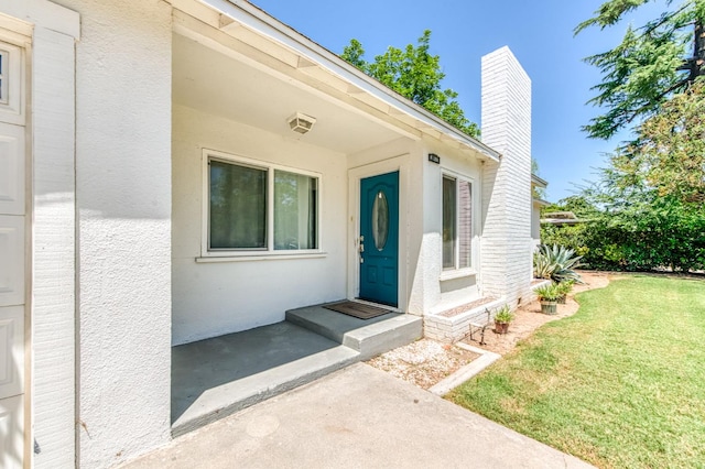 4611 N Safford Ave, Fresno, CA 93704 - view of exterior entry featuring stucco siding, a lawn, and a chimney