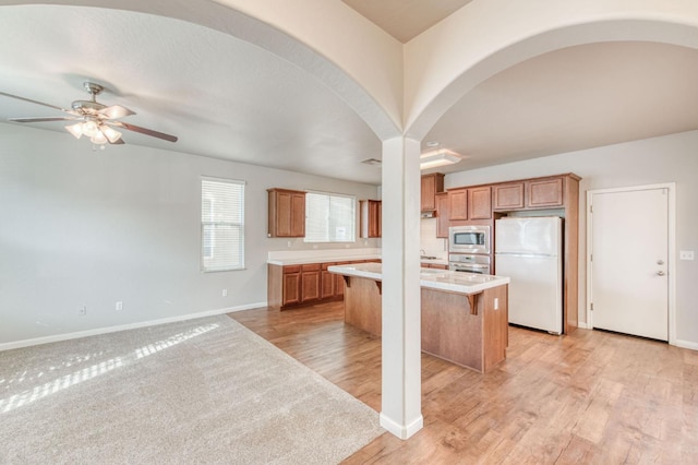 5516 N Sebastian Ln, Fresno, CA 93722 - kitchen with stainless steel appliances, a kitchen island, ceiling fan, light countertops, and a kitchen breakfast bar