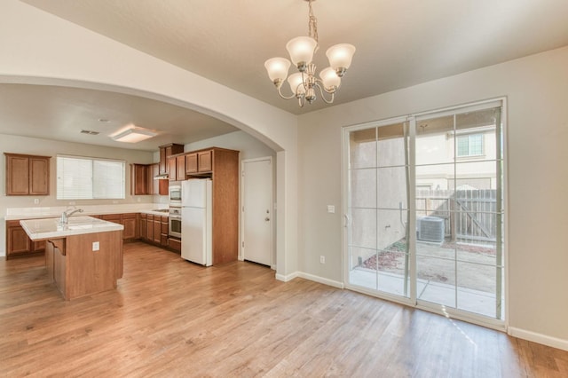 5516 N Sebastian Ln, Fresno, CA 93722 - kitchen featuring freestanding refrigerator, arched walkways, oven, light countertops, and brown cabinets
