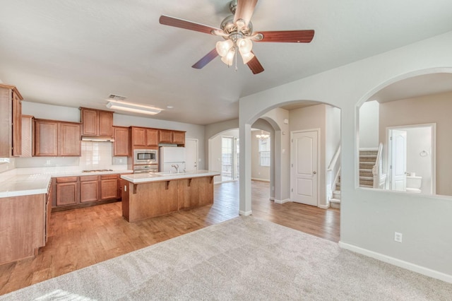 5516 N Sebastian Ln, Fresno, CA 93722 - kitchen with stainless steel appliances, a kitchen bar, arched walkways, ceiling fan, and a center island