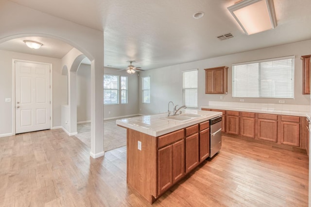 5516 N Sebastian Ln, Fresno, CA 93722 - kitchen with dishwasher, light wood-type flooring, ceiling fan, brown cabinets, and a center island with sink