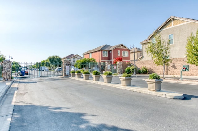 5516 N Sebastian Ln, Fresno, CA 93722 - view of asphalt road featuring curbs, a gate, a residential view, and sidewalks