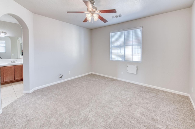 5516 N Sebastian Ln, Fresno, CA 93722 - empty room featuring light carpet, ceiling fan, healthy amount of natural light, and arched walkways