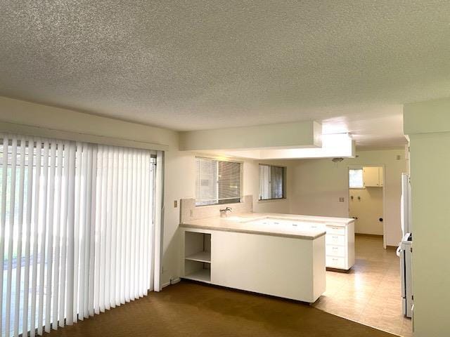 4902 E Townsend Ave, Fresno, CA 93727 - kitchen with a peninsula, a textured ceiling, light countertops, and tile patterned floors