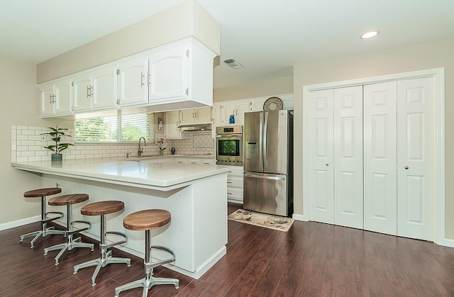 11851 Waverly Rd, Madera, CA 93636 - kitchen featuring appliances with stainless steel finishes, a peninsula, white cabinetry, dark wood-style flooring, and light countertops
