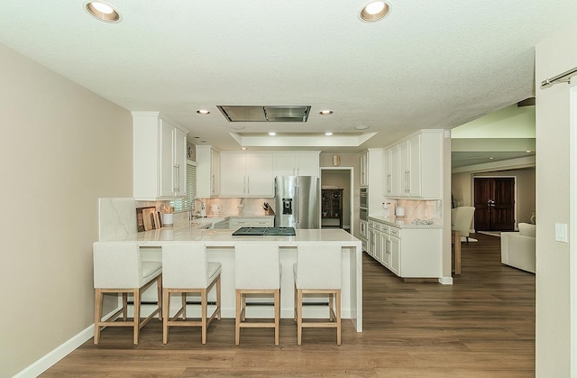 5383 N Briarwood Ave, Fresno, CA 93711 - kitchen featuring appliances with stainless steel finishes, a peninsula, backsplash, a breakfast bar area, and light countertops