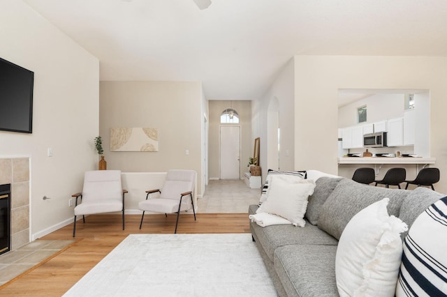9416 N Jade Ave, Fresno, CA 93720 - living area with arched walkways, light wood-type flooring, a tile fireplace, and a ceiling fan