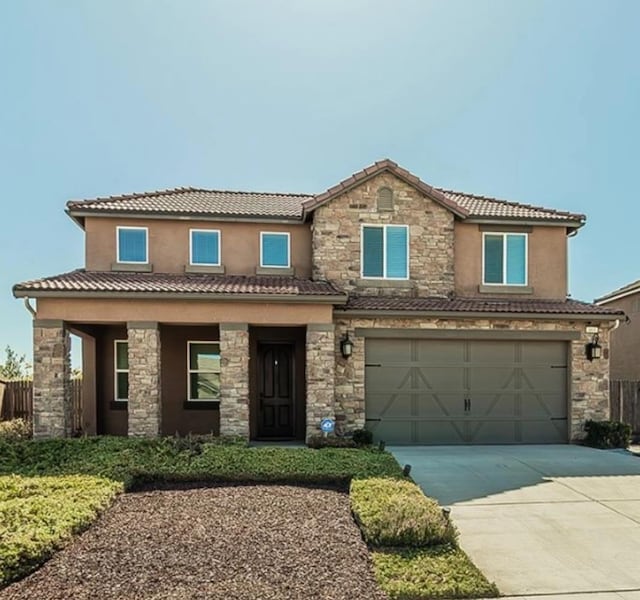 463 Mesa Dr S, Madera, CA 93636 - view of front of home featuring stone siding, driveway, an attached garage, a tiled roof, and stucco siding