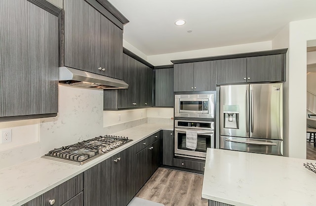 463 Mesa Dr S, Madera, CA 93636 - kitchen featuring appliances with stainless steel finishes, under cabinet range hood, light wood-style floors, and light stone counters