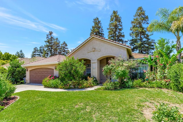 5613 W Bluff Ave, Fresno, CA 93722 - mediterranean / spanish home featuring a tiled roof, a front yard, stucco siding, an attached garage, and concrete driveway