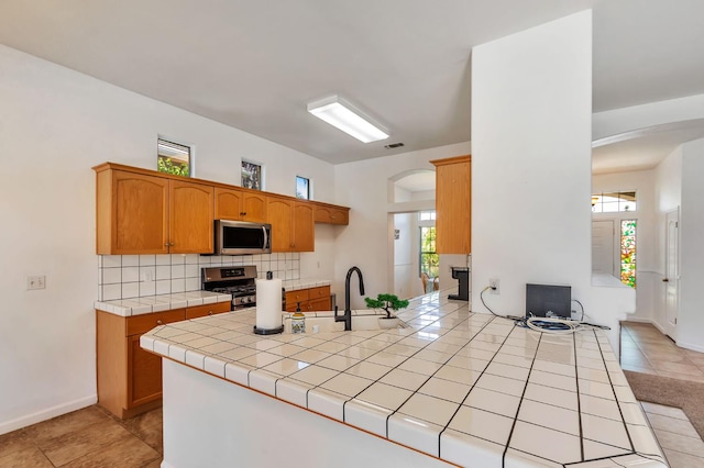 5613 W Bluff Ave, Fresno, CA 93722 - kitchen featuring stainless steel appliances, arched walkways, tile countertops, and healthy amount of natural light