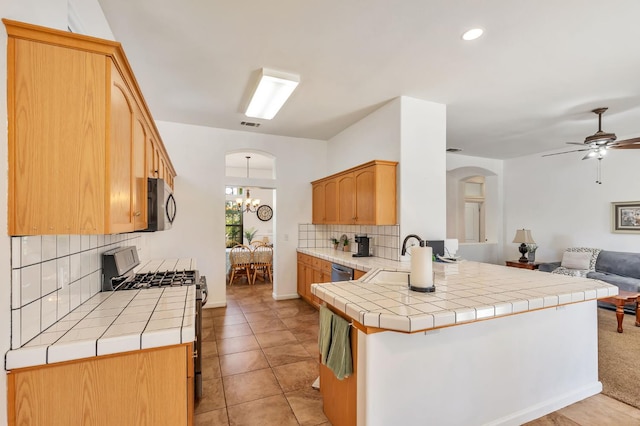 5613 W Bluff Ave, Fresno, CA 93722 - kitchen with gas stove, open floor plan, arched walkways, backsplash, and a peninsula