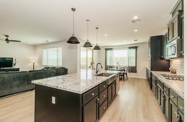 117 Emperor Way, Dinuba, CA 93618 - kitchen featuring appliances with stainless steel finishes, light wood-style floors, a center island with sink, plenty of natural light, and recessed lighting
