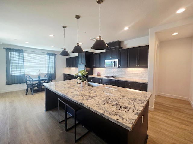 117 Emperor Way, Dinuba, CA 93618 - kitchen with stainless steel appliances, light wood finished floors, backsplash, light stone counters, and recessed lighting