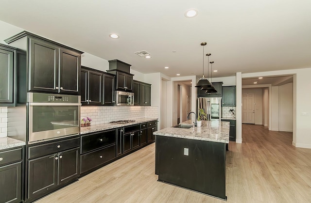 117 Emperor Way, Dinuba, CA 93618 - kitchen featuring appliances with stainless steel finishes, light wood-style floors, backsplash, light stone counters, and recessed lighting