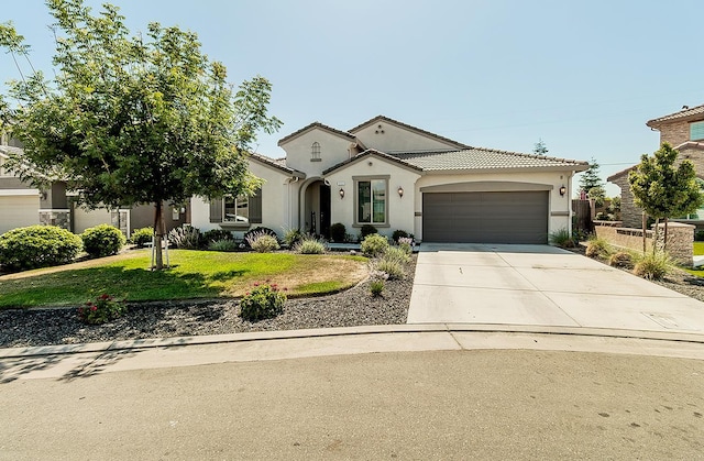 117 Emperor Way, Dinuba, CA 93618 - mediterranean / spanish home with an attached garage, concrete driveway, a front yard, stucco siding, and a tiled roof