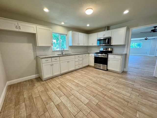 195 Hoover St, Coalinga, CA 93210 - kitchen featuring appliances with stainless steel finishes, decorative backsplash, light wood finished floors, white cabinetry, and recessed lighting