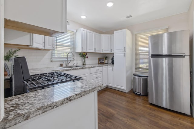 723 N Lourae Ave, Reedley, CA 93654 - kitchen featuring freestanding refrigerator, white cabinets, light stone counters, backsplash, and dark wood-style floors