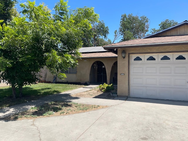 2327 S Martin L King Jr Blvd, Fresno, CA 93706 - view of front of property featuring stucco siding, an attached garage, solar panels, driveway, and a shingled roof