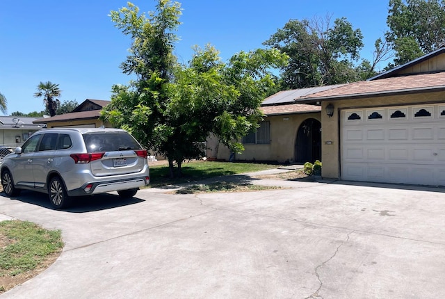 2327 S Martin L King Jr Blvd, Fresno, CA 93706 - view of front of home featuring driveway, roof mounted solar panels, stucco siding, and roof with shingles