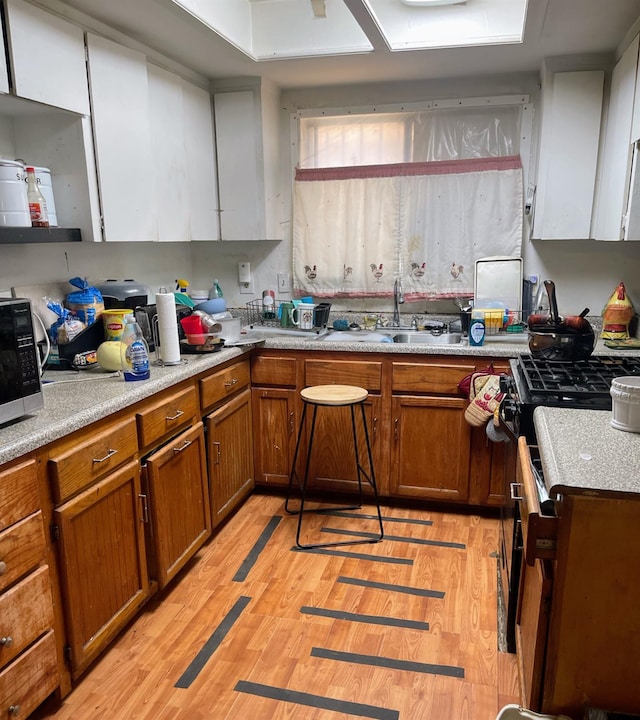 2327 S Martin L King Jr Blvd, Fresno, CA 93706 - kitchen with brown cabinetry, light wood finished floors, stainless steel microwave, and light countertops