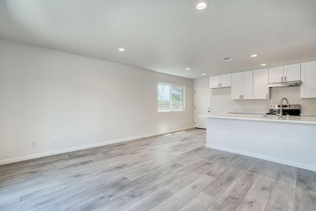 5276 N 1st St, Fresno, CA 93710 - kitchen featuring under cabinet range hood, light countertops, recessed lighting, light wood-style floors, and white cabinets