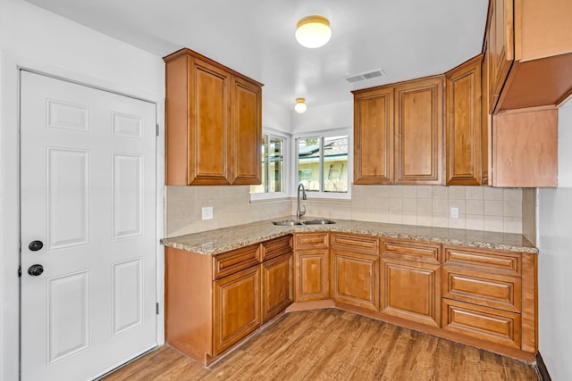 4759 E Vassar Ave, Fresno, CA 93703 - kitchen with brown cabinets, light stone countertops, light wood-style floors, and decorative backsplash